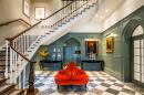 A hallway with stairs and a red chair.