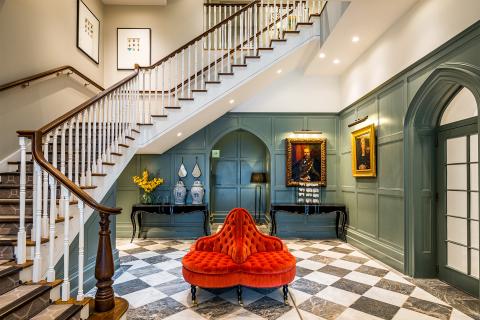 A hallway with stairs and a red chair.