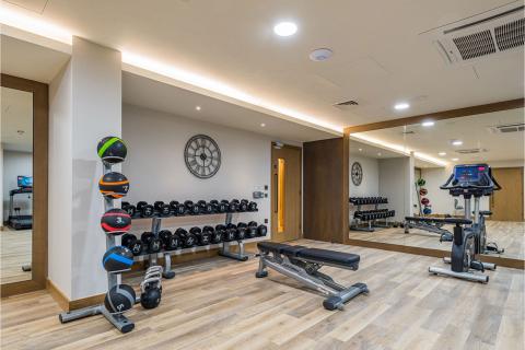 A gym room with weights and mirrors.