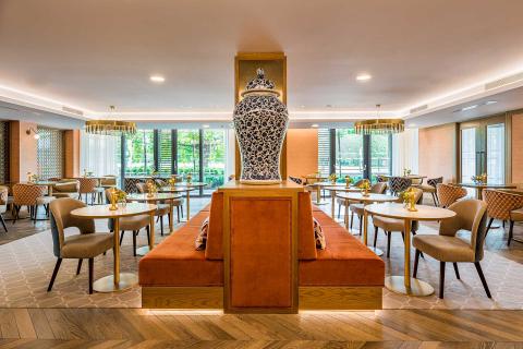 A restaurant with tables and chairs and a large vase.